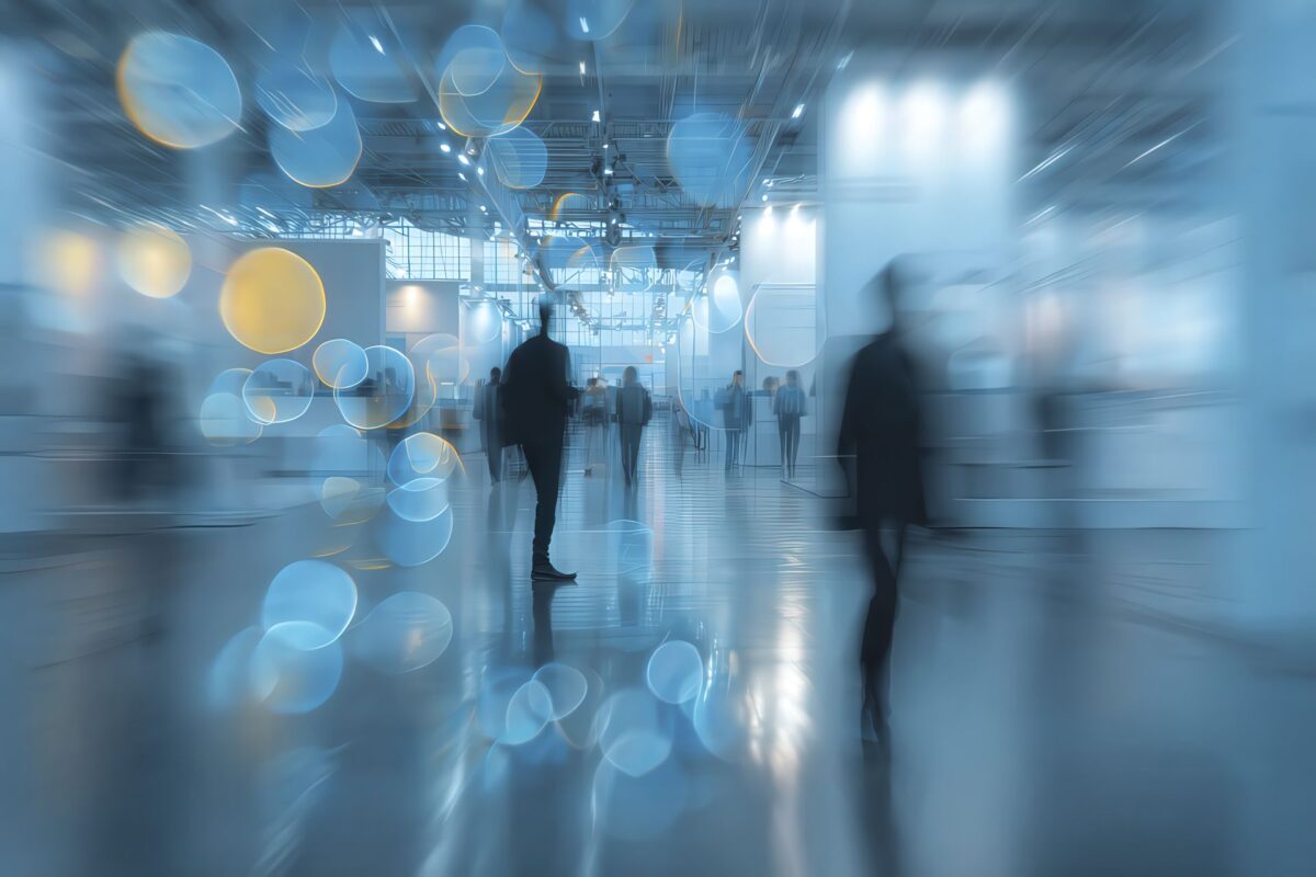 Persone in movimento tra espositori industriali, con effetti grafici di catene polimeriche blu e luce sostenibile